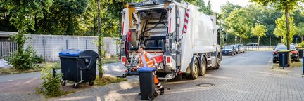 Ein Mitarbeiter der Bremer Stadtreinigung, der Papiertonnen leert. Im Hintergrund steht ein Müllfahrzeug. | © Die Bremer Stadtreinigung