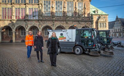 Vor dem Rathaus stellen Maike Schaefer, Daniela Enslein und eine DBS-Mitarbeitende die neue Elektro-Kleinkehrmaschine vor. | © Die Bremer Stadtreinigung